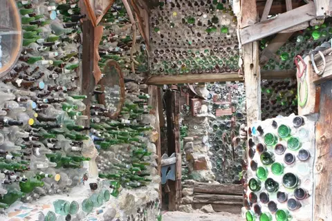 A structure built with countless glass bottles embedded into walls.