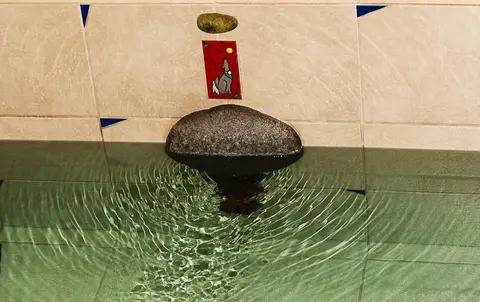 A water feature with a stone spout on a tiled wall.