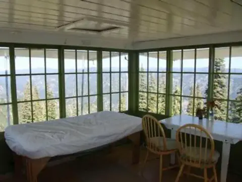 Inside view of a cabin with large windows showing a mountain landscape.