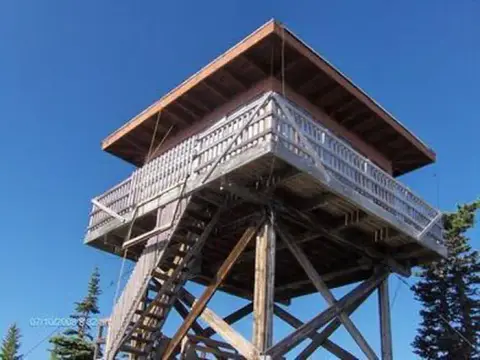 A wooden lookout tower stands against a blue sky.