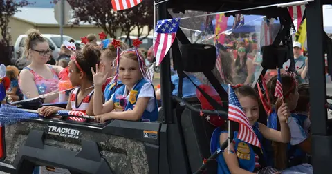 Children and adults ride in a decorated off-road vehicle during a parade.