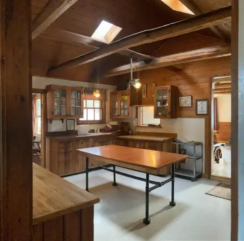 A rustic wooden kitchen with a large island and exposed ceiling beams.