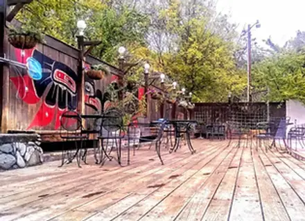 An outdoor wooden patio with tables, chairs, and a painted mural on the fence.