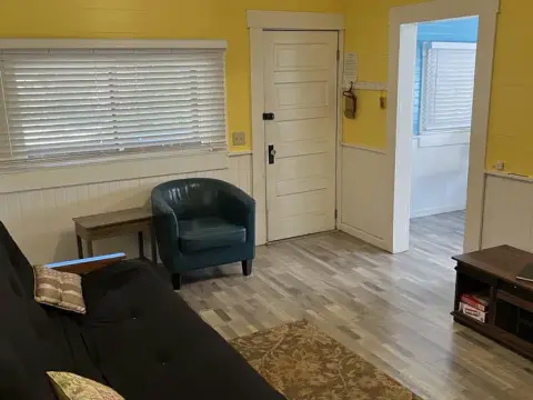 An interior room with yellow walls, a white door, and furniture.