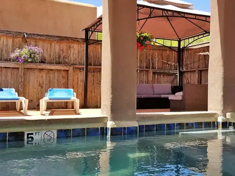 A swimming pool with lounge chairs and a gazebo in the background.