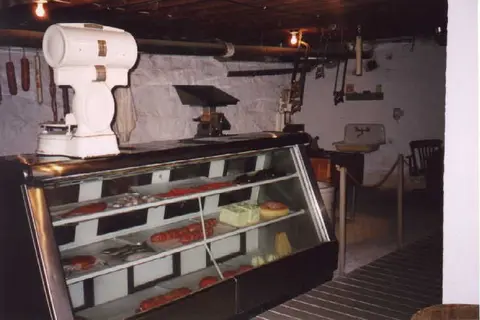 Interior view of a rustic meat display case and white scale.