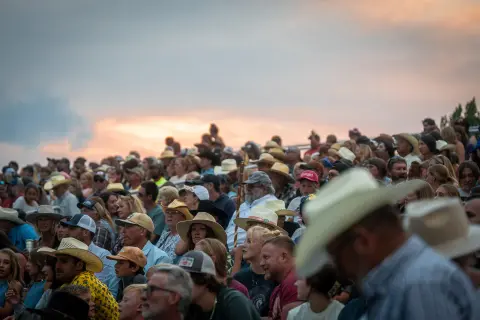 A large crowd watches an event at dusk.