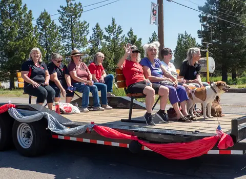 A group of people sitting on a decorated trailer float with a dog.