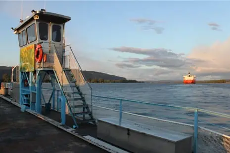 A control tower and stairs on a dock with a ship in the distance on the water.