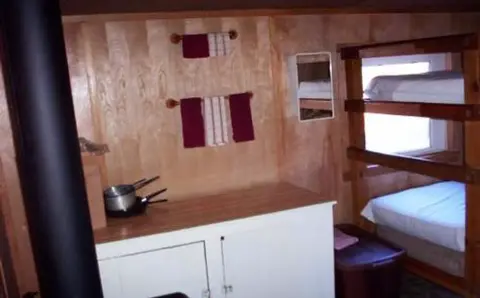 An interior view showing wooden paneling, a counter with cookware, and bunk beds.