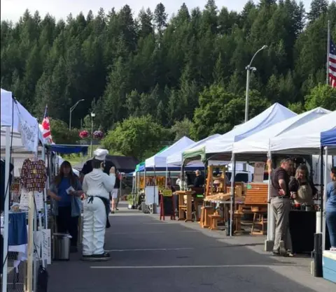 An outdoor market with white tents and vendors.