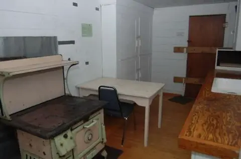 An interior view of a room with a vintage stove, table, and wooden counter.