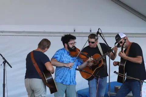 A band performs on a stage, playing string instruments.