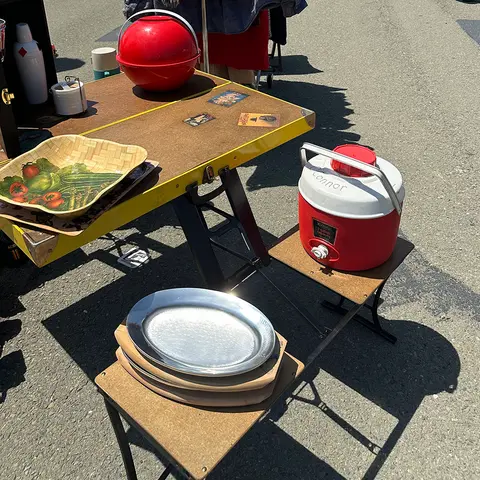 A folding table and small stands display various items at a flea market.
