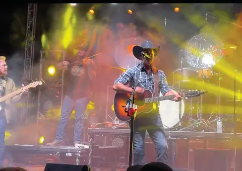 A band performs on stage under colorful stage lights.