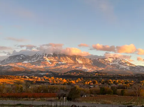 A scenic landscape view of snow-dusted mountains at sunset with a valley in the foreground.