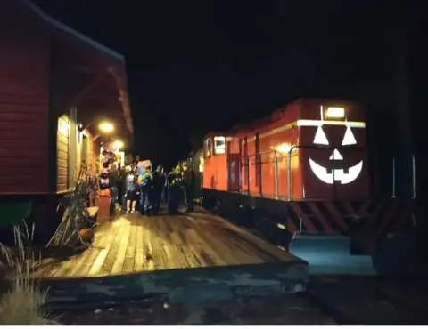 A decorated train sits by a station platform at night.