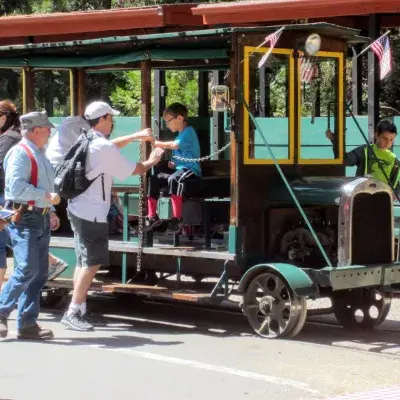 People boarding a small tour train vehicle.