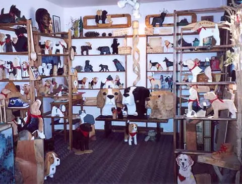 A room filled with wooden shelves displaying various carved wooden animals and figurines.