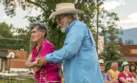 An older couple dances outside outdoors.