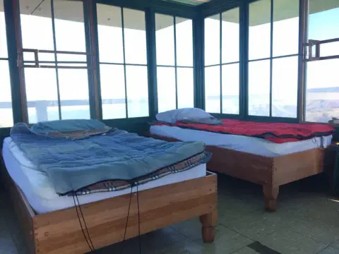 Two beds inside a room with large glass windows.
