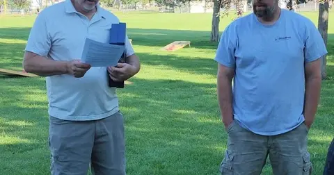 Two men standing outside on a grassy field.