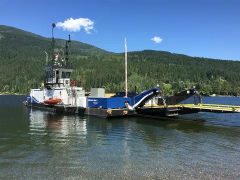 A ferry boat on a lake with green hills in the background.