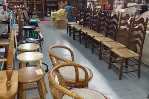 A photograph showing an indoor view of a store filled with various chairs and stools.
