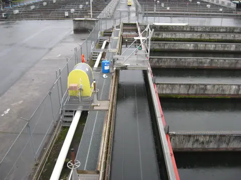 A high-angle view of a large water treatment facility with concrete basins and metal walkways.