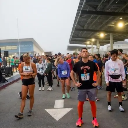 A group of runners stand outdoors waiting for a race to start.