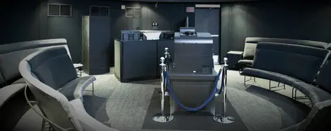 A dark planetarium interior with curved seating and control equipment.