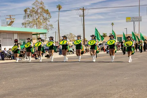 A parade group carrying letter signs walks down a street.