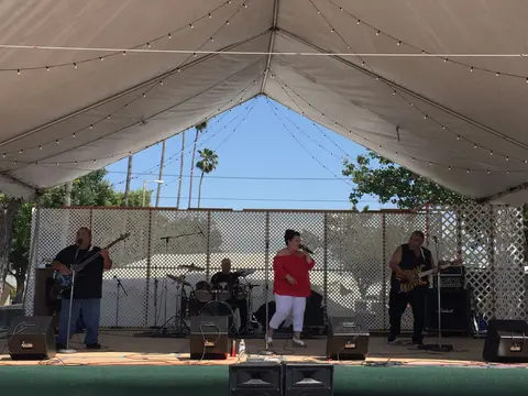 A band performs on a stage under a white tent.