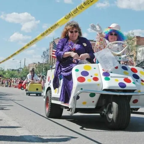 People ride in decorated golf carts in a parade.