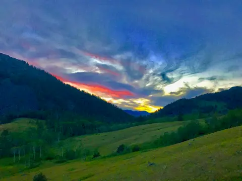 A colorful sunset over rolling green hills and mountains.