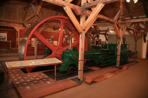 A large vintage industrial engine inside a rustic wooden building.
