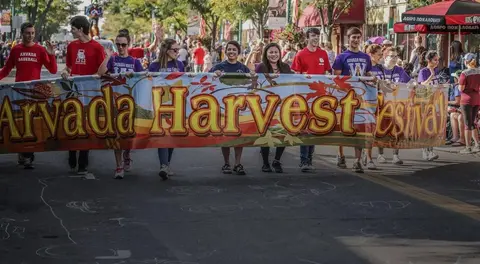 People carry a festival banner down a street.