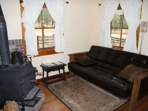 An interior view of a room with a sofa, wood stove, and small windows.