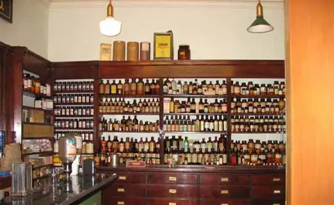An interior view showing wooden shelving filled with numerous glass bottles and containers.