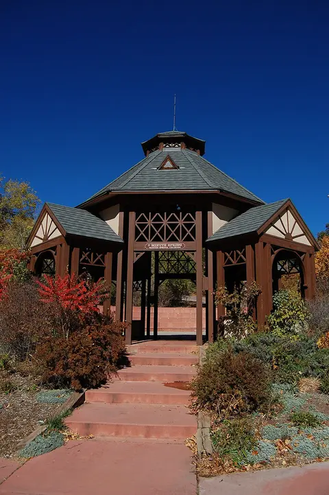 An outdoor gazebo with wooden beams and a tiered roof set against a blue sky.