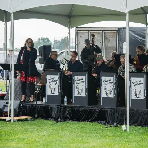 A band performs under a white tent on a grassy area.