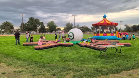 People enjoy inflatable games set up on a grassy field.