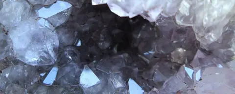 Close-up view of the inside of an amethyst geode with purple crystals.