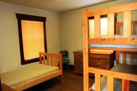 A bedroom with wooden bunk beds and a single bed.