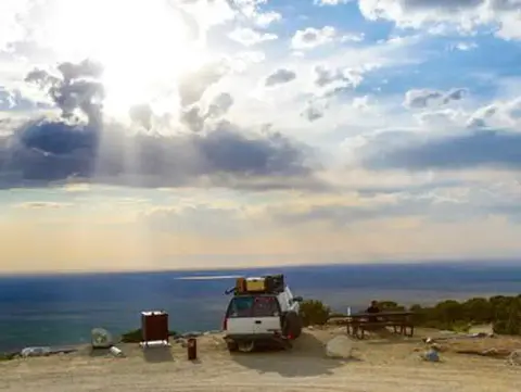 A vehicle parked at a scenic overlook beneath a cloudy sky.