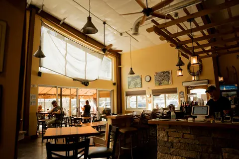 An interior view of a restaurant or tasting room with tables, a bar, and customers.