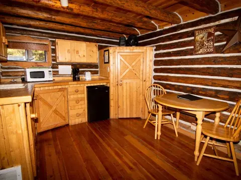 This photo shows the interior of a rustic log cabin kitchen and dining area.