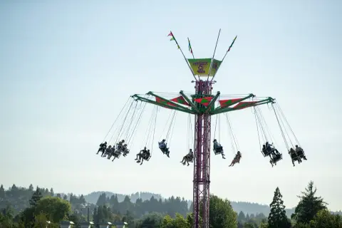 A tall swing ride at an amusement park with people riding it.