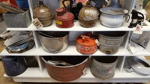 Various vintage household and farm items displayed on white shelves.