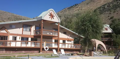 A resort building with a pool and deck area set against a hillside.